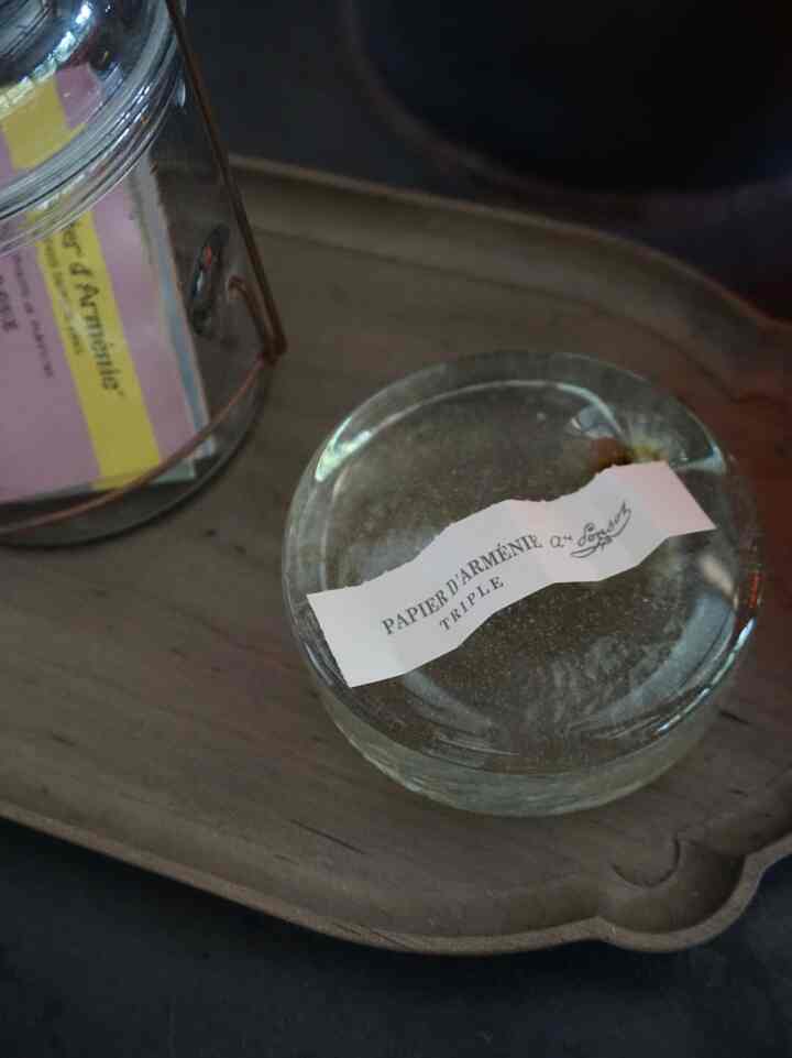 Natural wood tone tray holding a clear glass container and fragrance paper in a calm setting
