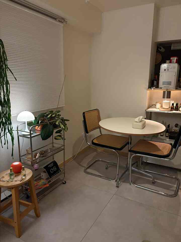 白とシルバーのトーンでまとめたミッドセンチュリーモダンのダイニング、棚と植物が調和する印象的な空間