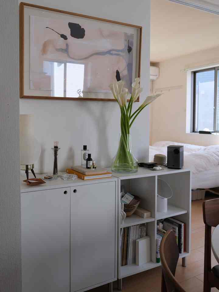 白を基調とした寝室、花瓶と収納棚が配置された清潔感のあるモダンなインテリア
