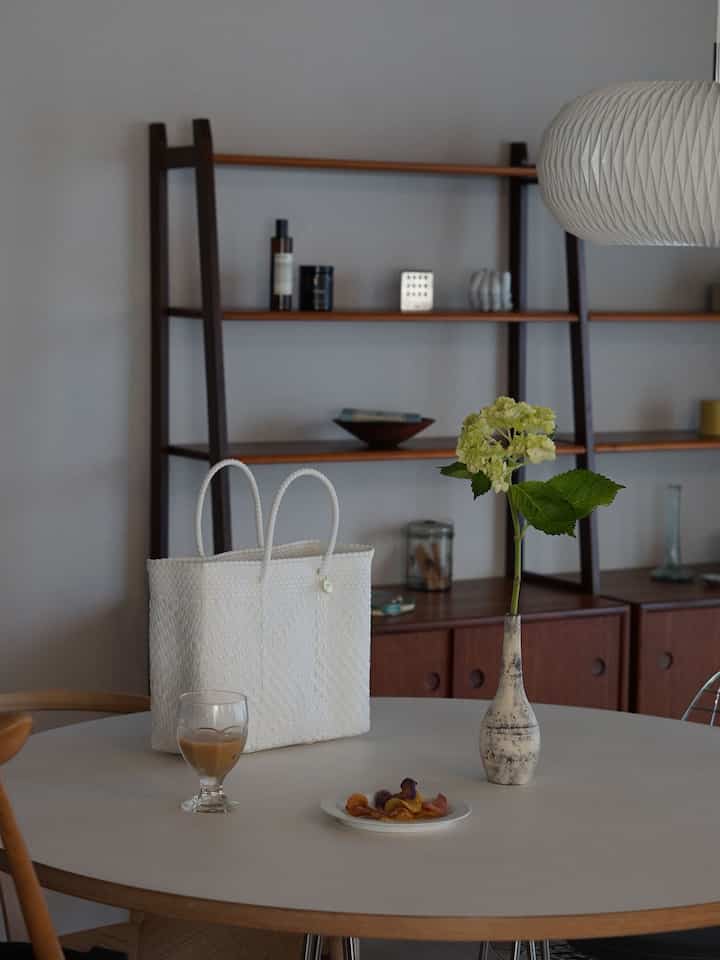 Natural color and wood tone dining room featuring a round table with a white bag and vase, creating a minimalistic space