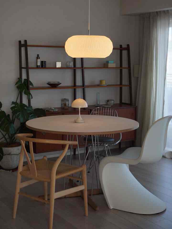 White-toned dining space with wood accents featuring a round dining table and mixed chairs in a cozy living-dining interior