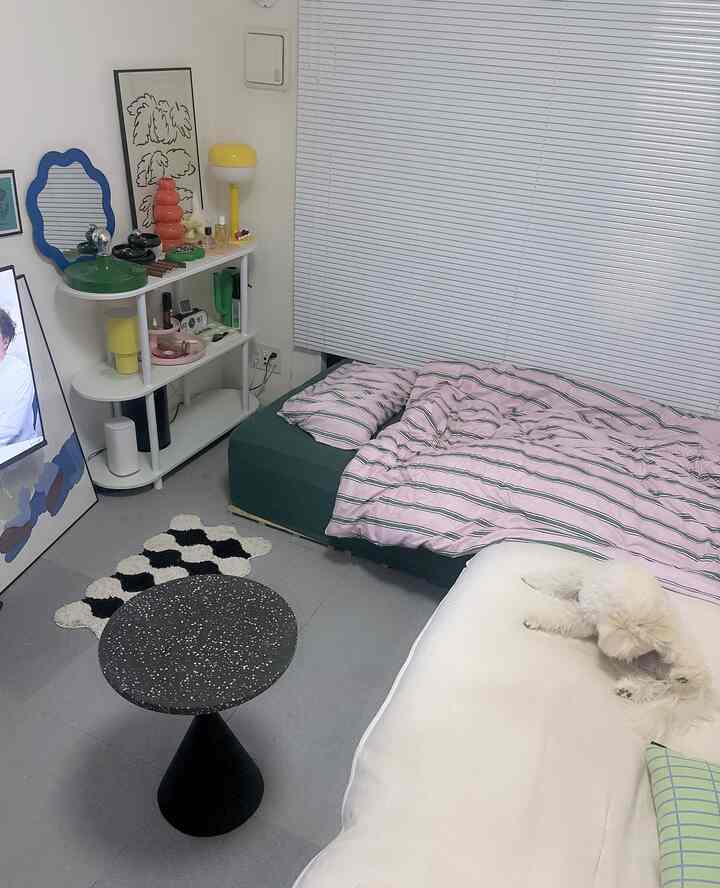 白と緑のトーンの寝室、ベッドとサイドテーブル、ソファに横たわるふわふわの犬がいる雰囲気のあるインテリア