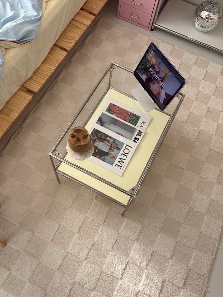 ステンレスフレームと黄色の天板のローテーブルがチェック柄の白いラグの上に置かれたナチュラルなリビングルーム