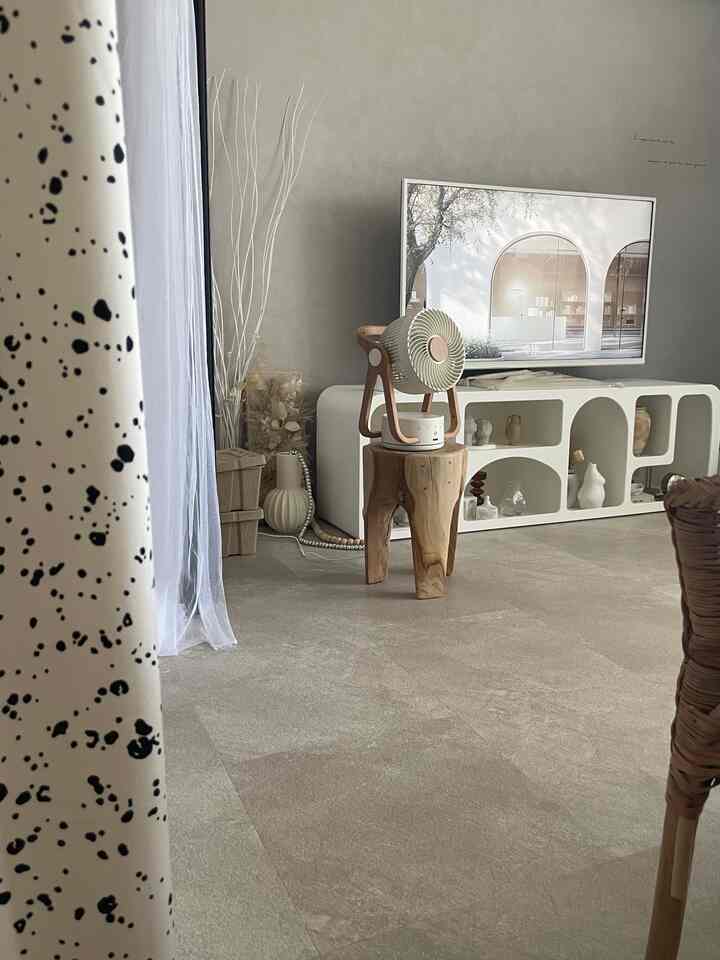 ナチュラルな色調のリビング、白いテレビ台と木製スツールの上に小さなサーキュレーターが置かれたシンプルなインテリア