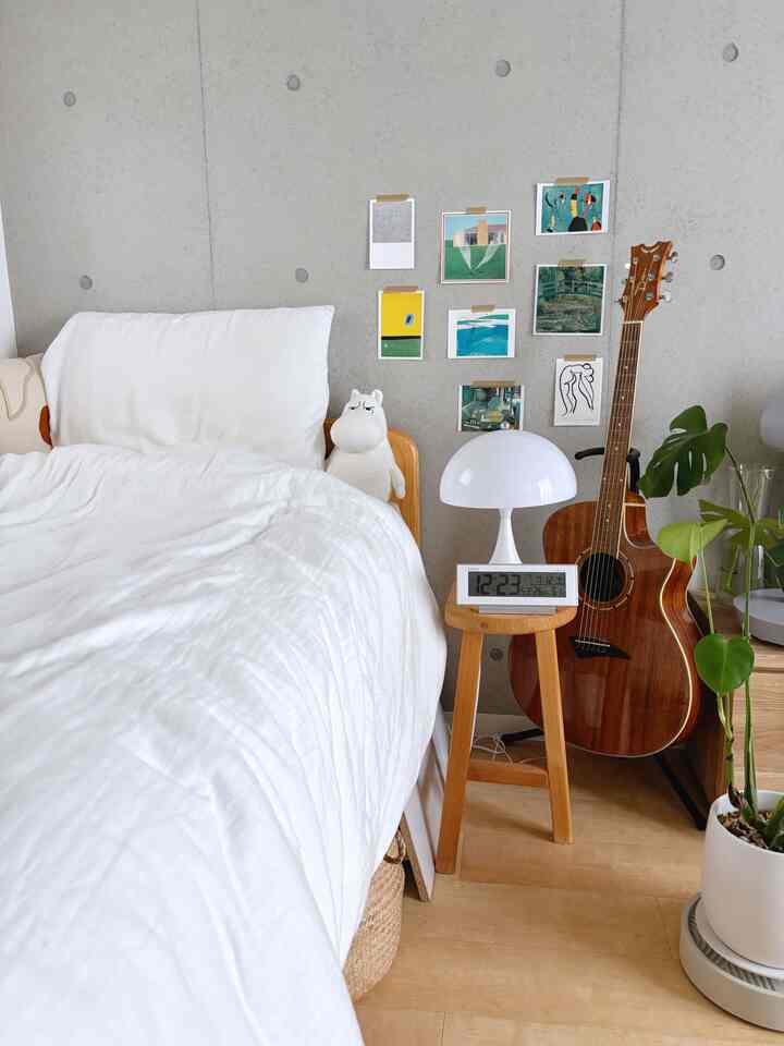 白と木目調が調和したナチュラルな北欧スタイルの寝室、アートウォールと植物を配した雰囲気あるベッドサイド