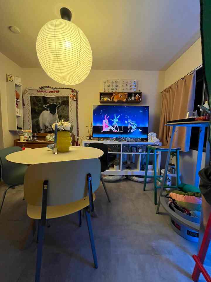 ホワイトとイエローのトーンの1LDKのリビング兼ダイニングルーム、木製収納ボックスとテレビ台が配置されたミッドセンチュリーモダンスタイルの落ち着いた空間