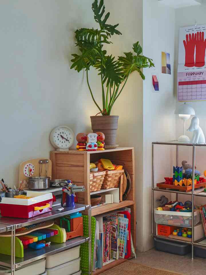 ホワイトとナチュラルカラーの子供部屋、さまざまなおもちゃと収納が配置された温かみのある少し散らかった印象的な空間