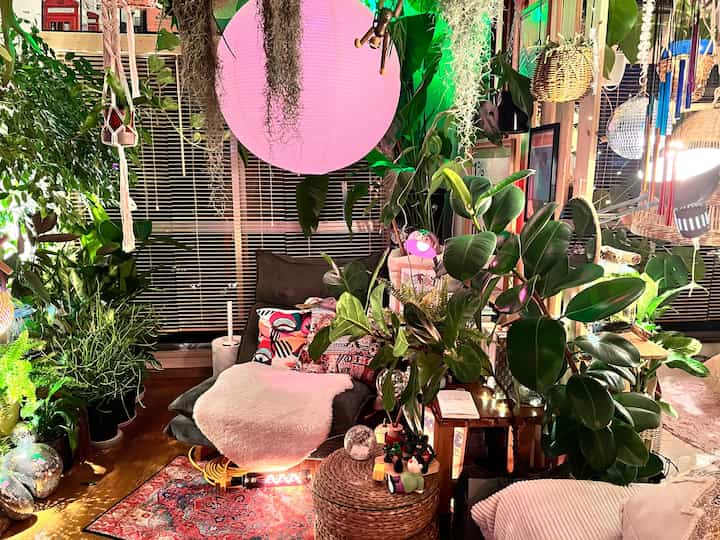 Colorful living room interior featuring pink lighting and abundant plants with a cozy atmosphere