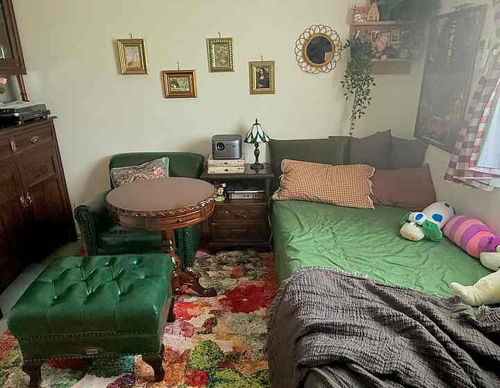 A vintage natural-tone bedroom featuring a green bedspread and green leather ottoman with cozy atmosphere
