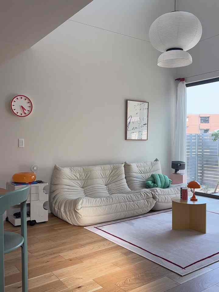 ホワイトと木目調が調和したリビング、丸いサイドテーブルと特徴的なソファが配置された雰囲気のあるインテリア