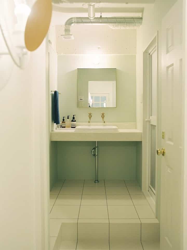 白とベージュの落ち着いた色調のバスルーム、洗面台と鏡が配置されたホテルライクな雰囲気のインテリア