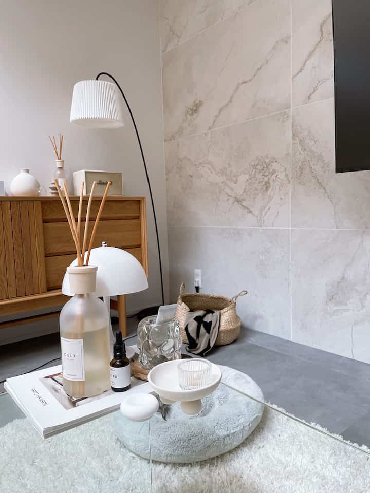 White and wood tone living room featuring a glass coffee table with diffuser and candle creating a cozy atmosphere
