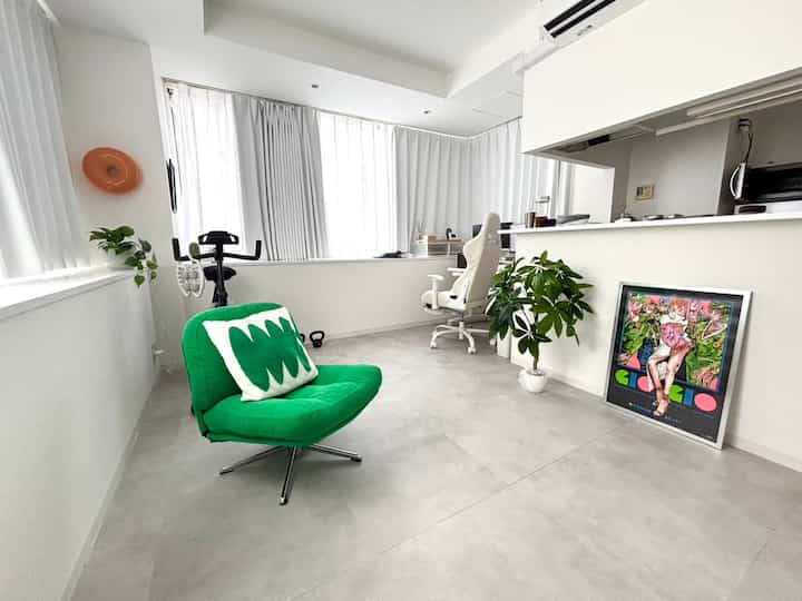 白と緑を基調とした1LDKのモダンなインテリア、アームチェアとオフィスチェアが配置されたミニマルな空間