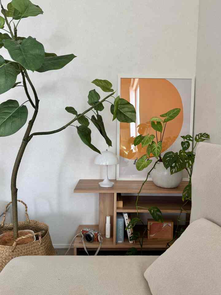 明るい白と茶色の木目調が調和したリビング、ベージュのソファと多彩な植物が印象的な雰囲気を演出しています。