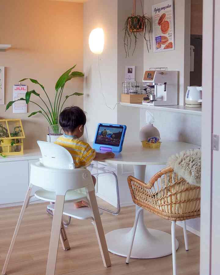 白とナチュラルカラーのダイニングルーム、子供がキッズタブレットを使いながらダイニングチェアに座っている雰囲気のあるインテリア
