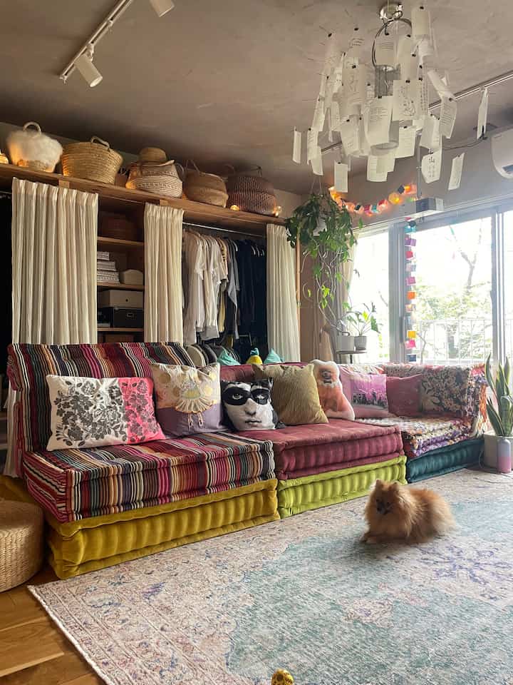 A colorful multicolor sofa and rattan baskets in a vintage-style living room featuring a small dog sitting on a rug
