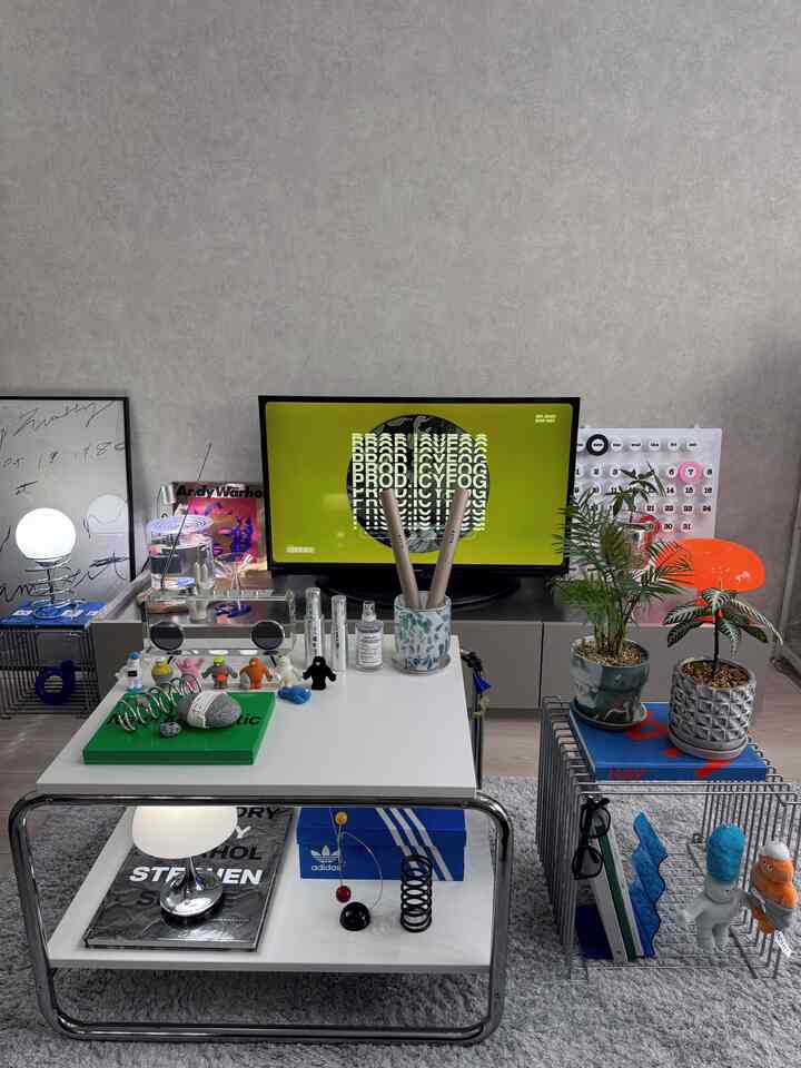 白とグレーのトーンのリビング、ミッドセンチュリーモダンのテーブルと植物が配置された雰囲気のある空間