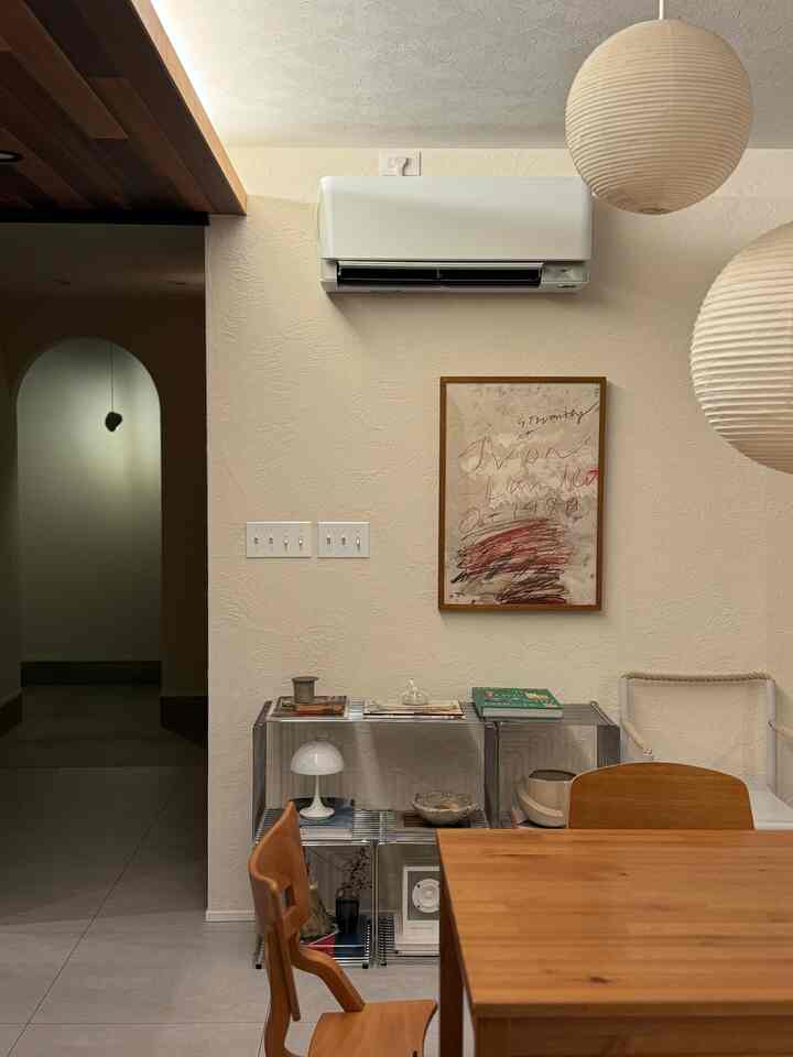 ベージュとナチュラルな木目調のダイニング、ペンダントライトとミッドセンチュリーモダンの家具が配置された落ち着いた空間