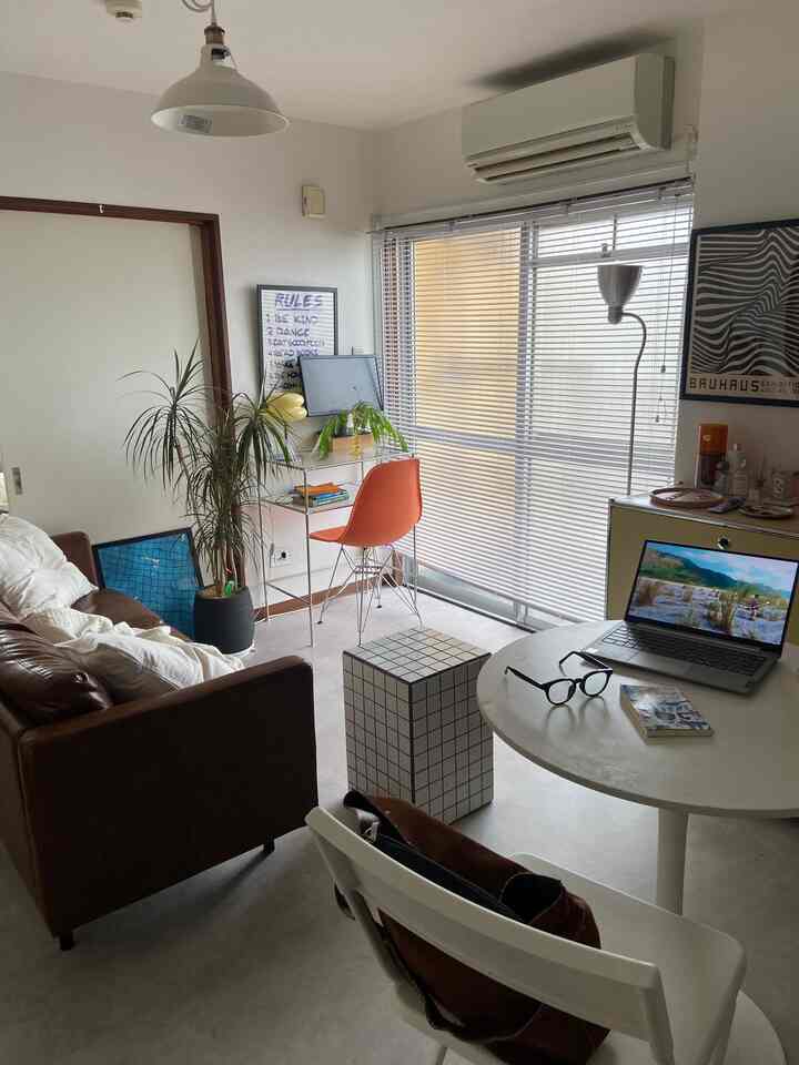 White and brown toned living room for a single household featuring a compact home office desk and sofa in Mid-Century Modern style