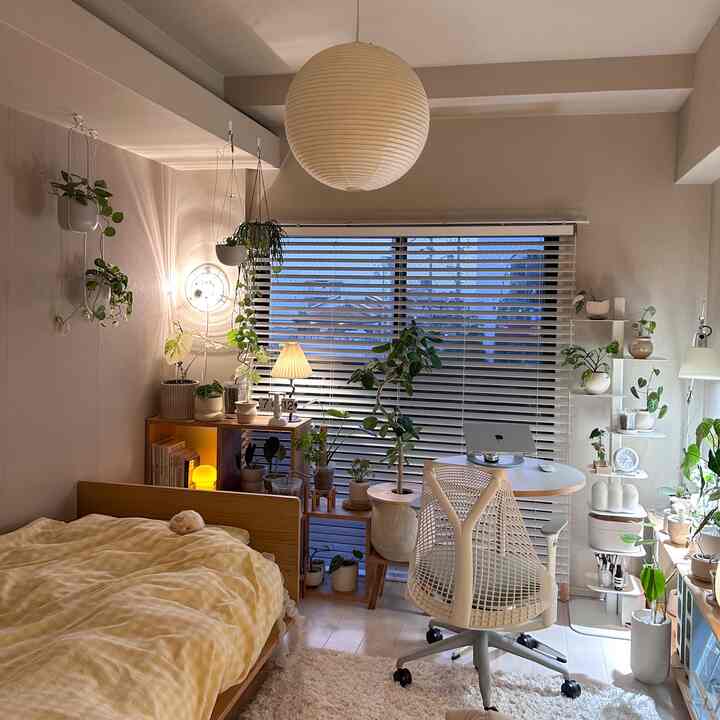 Light beige and white toned bedroom featuring a cozy home office with natural light and abundant plants