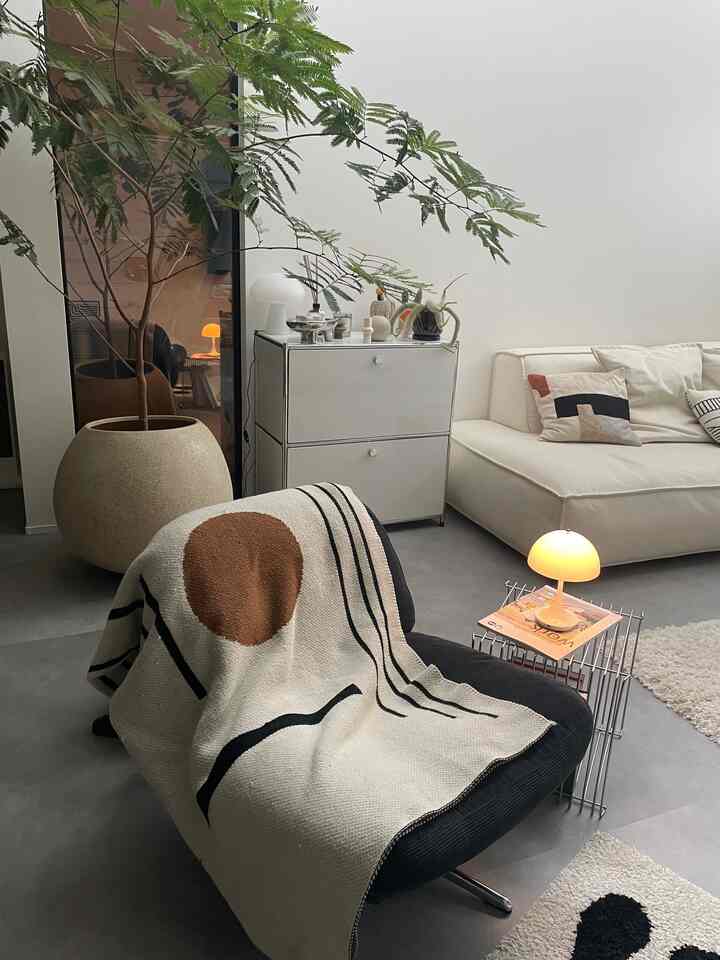 白と黒のナチュラルなリビング、ソファとアームチェアが配置されたシンプルで落ち着いた空間