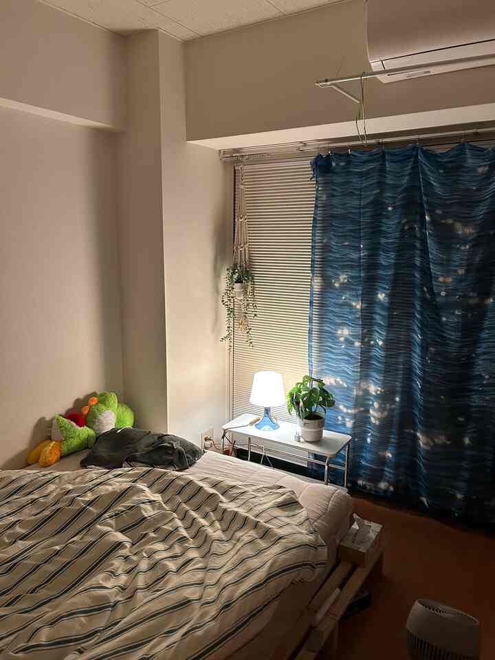 白とブルーのトーンの寝室、ベッドと棚、ブラインドが配置された落ち着いた雰囲気のインテリア