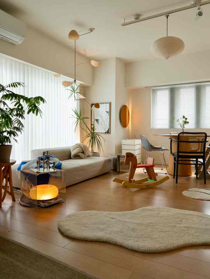 ナチュラルカラーと木目調のリビング、ベージュのソファと木製ダイニングテーブル、赤ちゃん用の木馬が配置された雰囲気のある空間