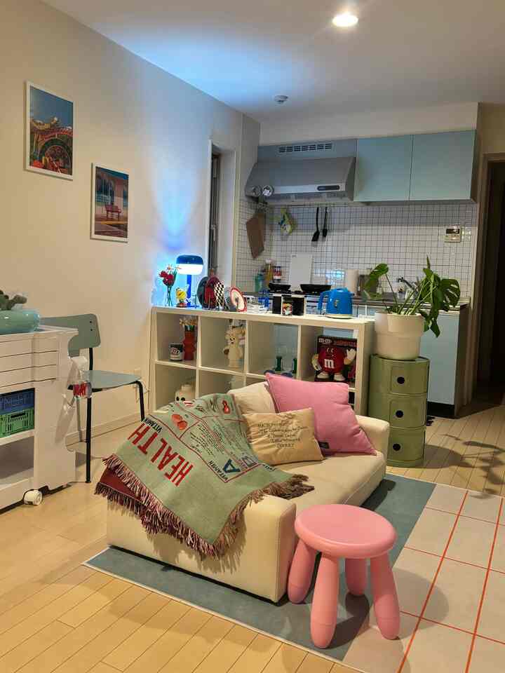 ホワイトとミントカラーの1LDKオープンキッチン兼ダイニングルーム、パステルピンクのスツールとカラフルな小物が調和した雰囲気のある空間