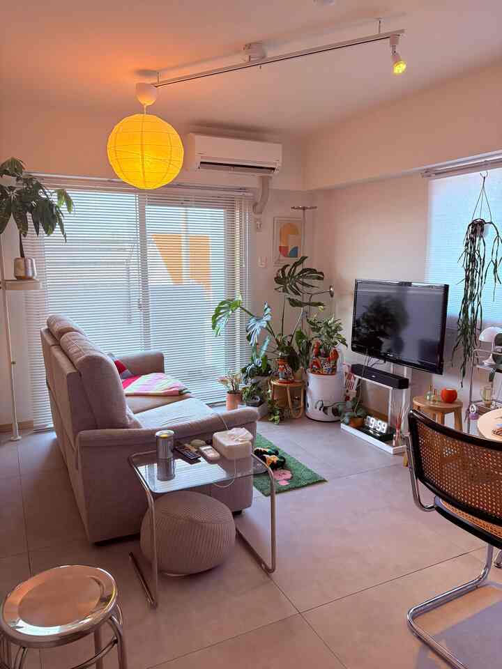 ライトグレーのトーンが特徴の1LDKリビング、グレーのソファと黄色のペンダントライトが配置された自然でモダンなインテリア