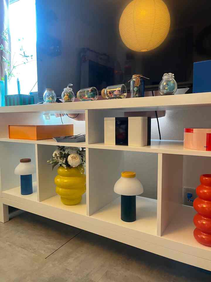 明るいオレンジと黄色の花瓶と照明が配置された1LDKのミッドセンチュリーモダンなリビング用テレビ台と収納棚