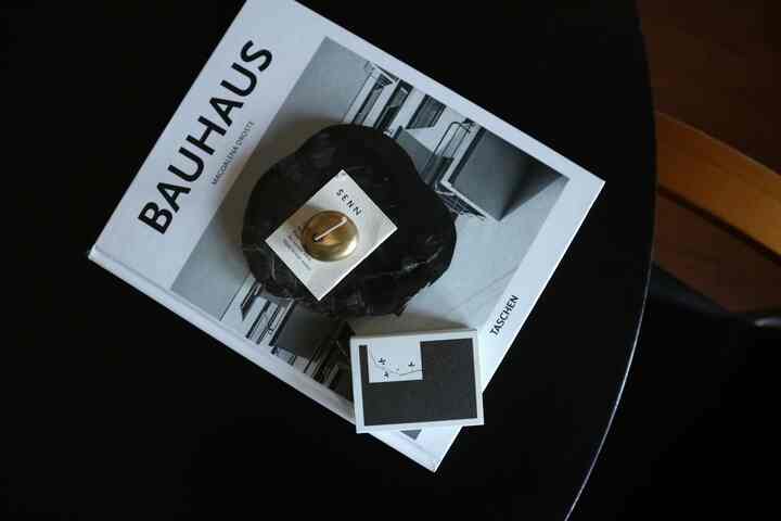 黒いコーヒーテーブルの上にミッドセンチュリーモダンのバウハウスの本とキャンドルが配置されたモダンなリビング