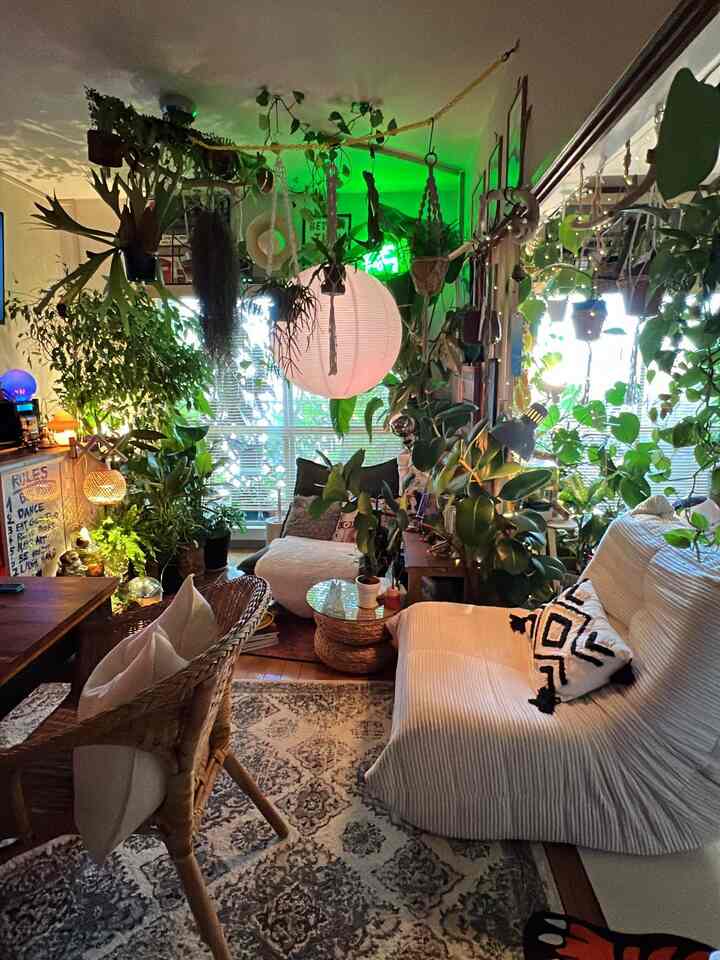 緑豊かな植物と白いラタンチェアが配置された縦長のナチュラルなリビング空間