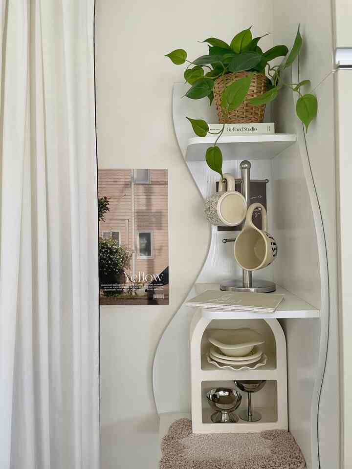 Pastel-toned kitchen shelf featuring mugs and a plant in a cozy arrangement