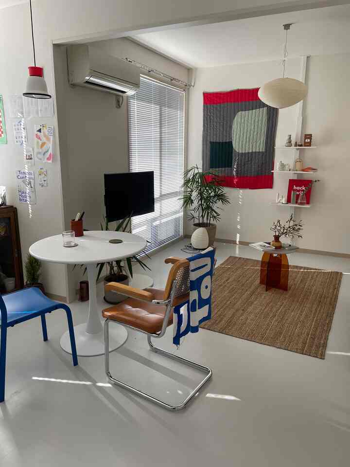 Bright white-toned studio apartment living and dining area featuring natural brown rug and modern Nordic style furniture