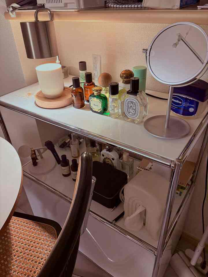 ホワイトとクロームのモジュール家具キャビネットの上に香水と照明が配置された、ミッドセンチュリーモダンスタイルの化粧台空間