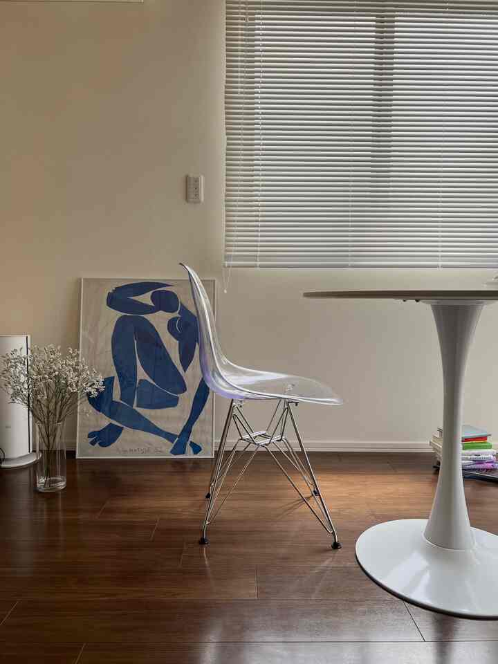 透明なプラスチックチェアと白い丸テーブルが配置されたナチュラルトーンのワンルーム空間