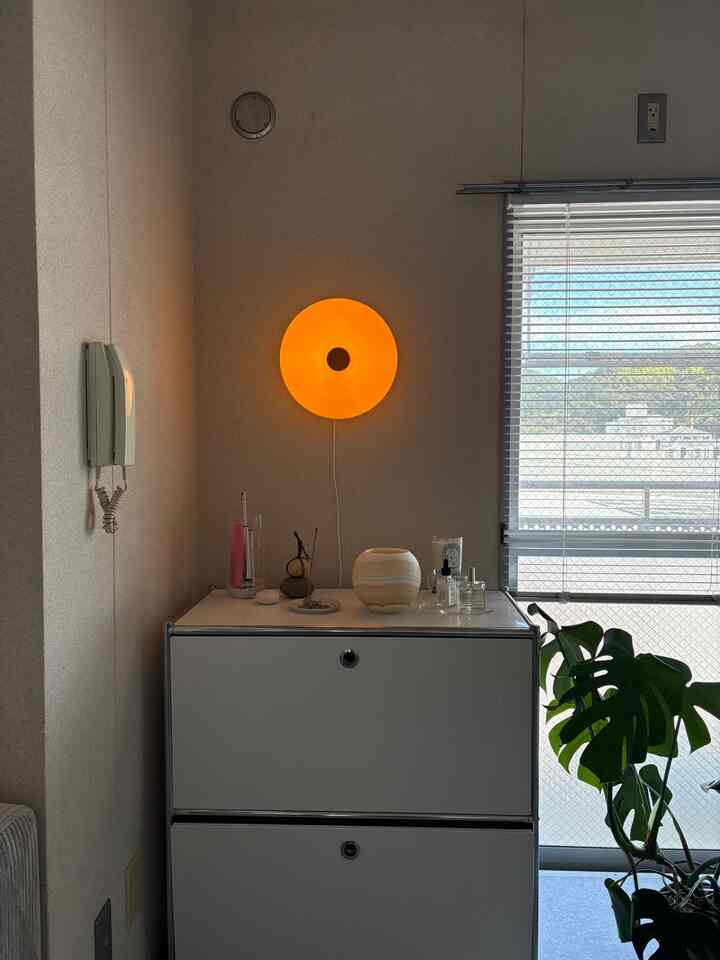 暖かいオレンジの照明と白い収納がある清潔感のあるダイニング空間、ウッドトーンと植物がアクセントの落ち着いたインテリア