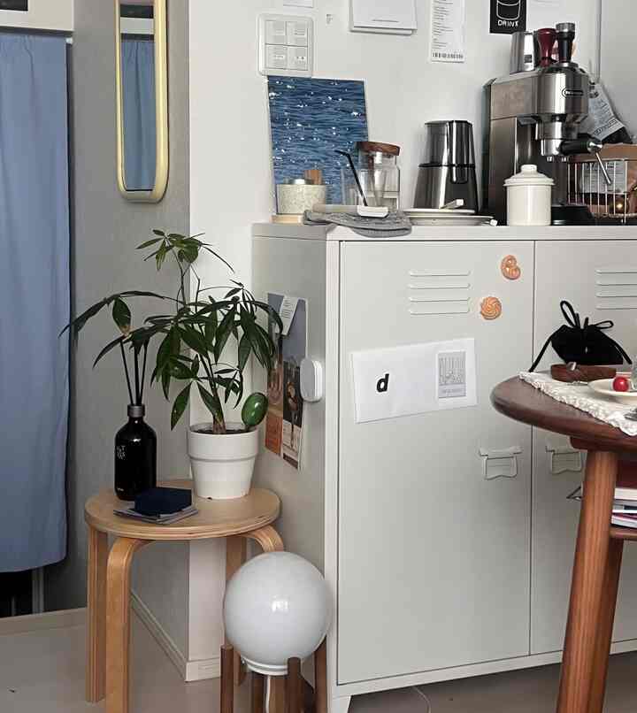 白と青のトーンのキッチンとダイニングスペース、ミニマルな家具とコーヒー器具が配された印象的な一人暮らしの空間