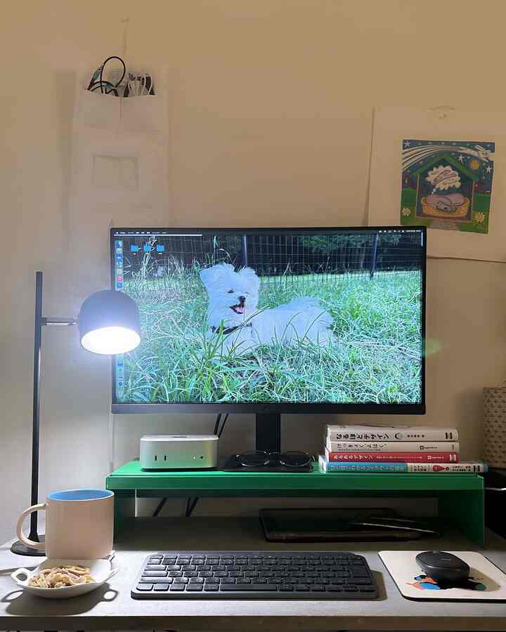白い壁と緑のモニター台がある一人暮らしの1Kワークスペース、間接照明と作業用具が配置された雰囲気のあるインテリア