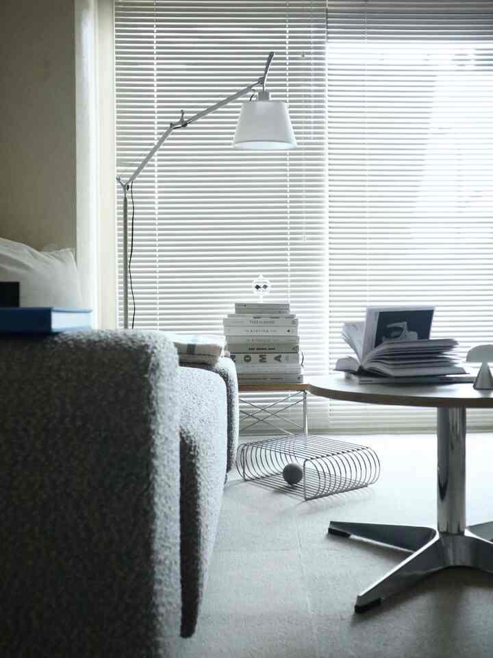 グレーとホワイトのトーンの清潔感あるリビング、テクスチャ豊かなソファとラウンドコーヒーテーブル、調整可能なフロアランプが配置された印象的な空間