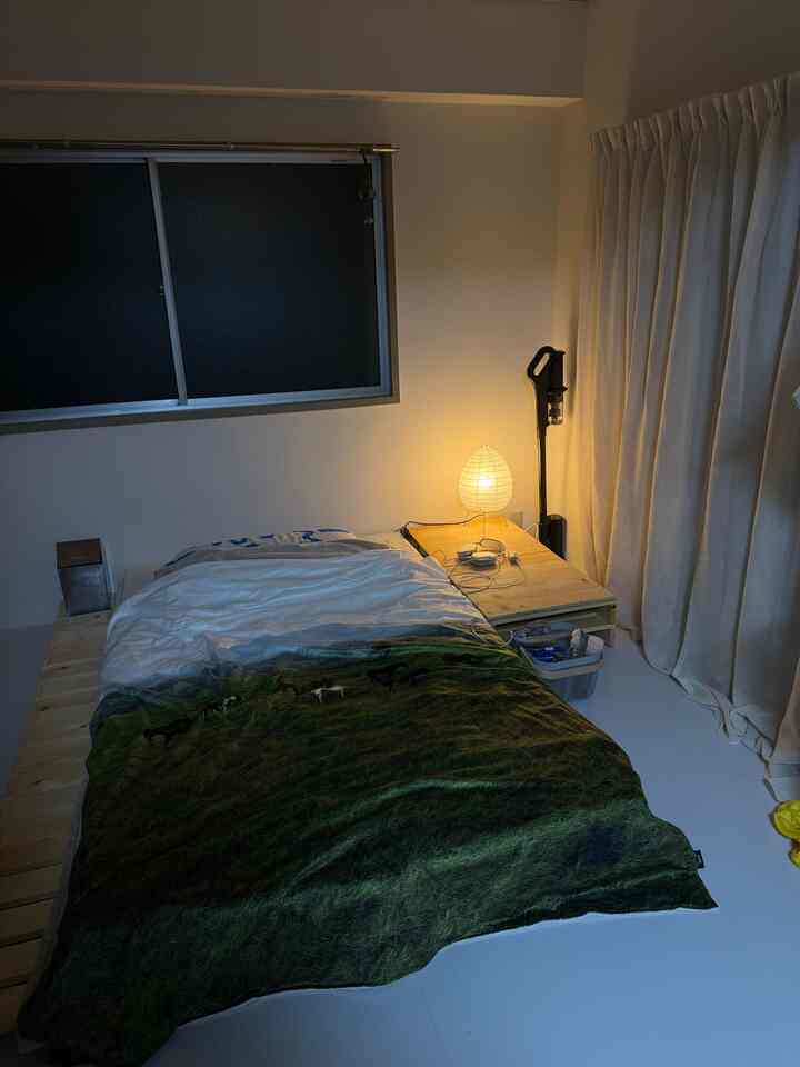 白と木目調の寝室、シングルベッドと間接照明が配置された落ち着いた雰囲気の空間