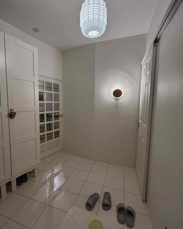 白を基調とした玄関スペース、壁照明と大きなクローゼットが配置された清潔感あるインテリア