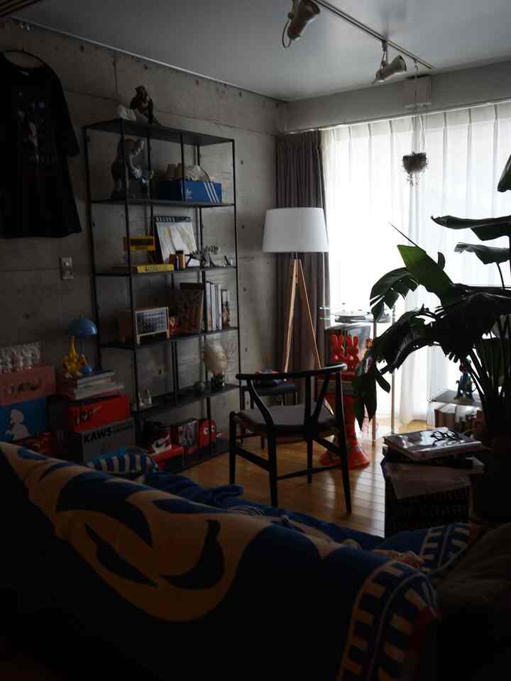 ブラウンの木製フローリングとブルーのブランケットが目を引く1LDKのリビング、ミッドセンチュリーモダンの家具とフロアランプが配置されたモダンな空間