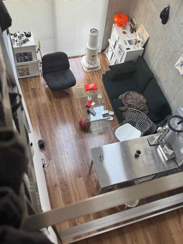 ブラウンのウッドフロアとブラックのアームチェア、ダークグリーンのソファが配置された小さなワンルームのリビング