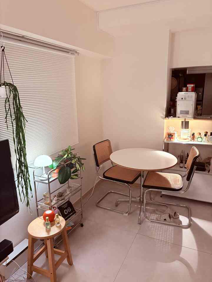 白を基調としたミッドセンチュリーモダンな丸テーブルが配置された、シンプルで開放感のある韓国風インテリア空間