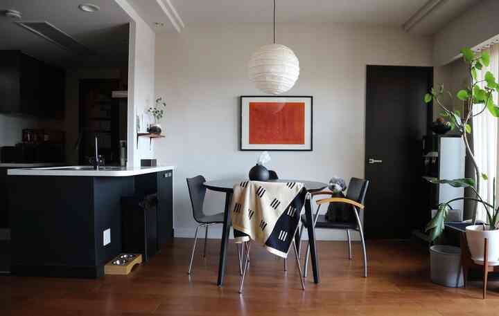 Mid-Century Modern dining room with wood-toned floor and black dining table, featuring a dog and green plants in a cozy setting