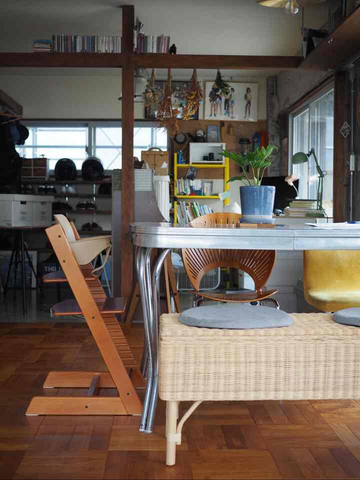 木目調とシルバーのテーブルが調和するリビング兼ダイニングルーム、ラタンのベンチと多様な椅子が自然で落ち着いた雰囲気を演出