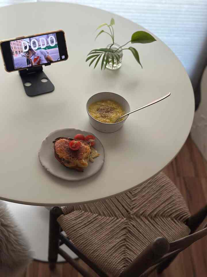 Minimal dining room in white and wood tones, cozy space with round table featuring food and plant