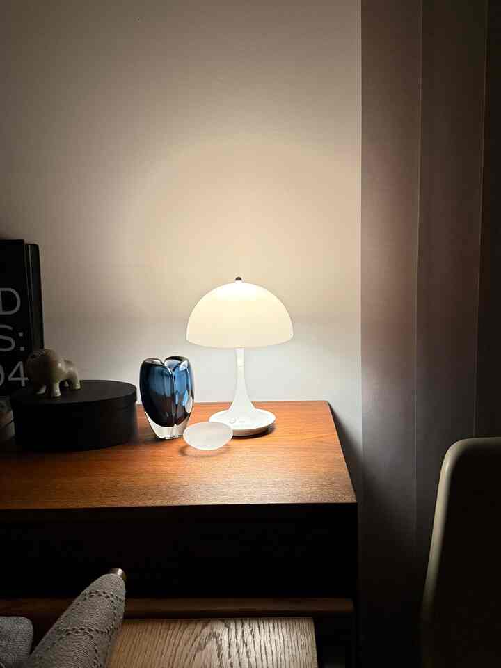 Cozy space featuring white and wood tones with a table lamp and decorative objects arranged on a wooden side table