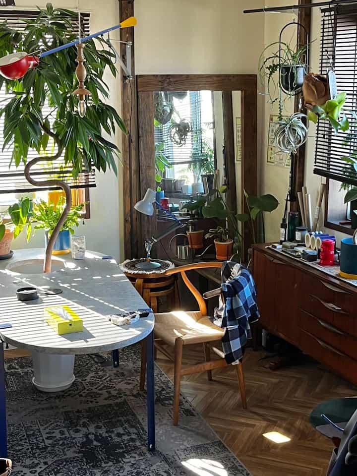 ナチュラルな木目調と植物が調和したダイニングルーム、大きな鏡と快適なダイニングチェアが配置された温かみのある印象的な空間